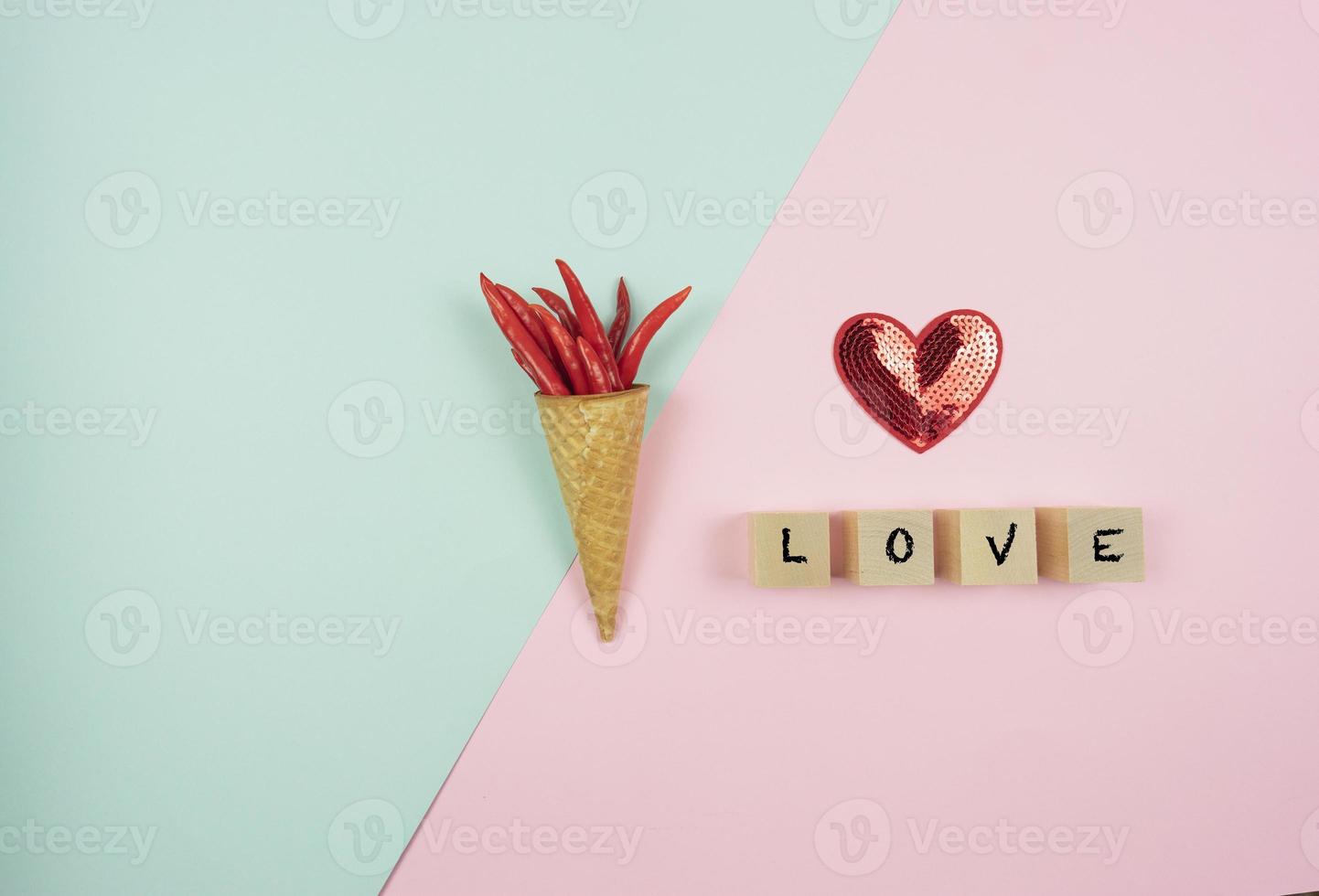 Red hot peppers in the waffle cone and a red heart lie on a colorful background. Words letters love written on a wooden cubes photo