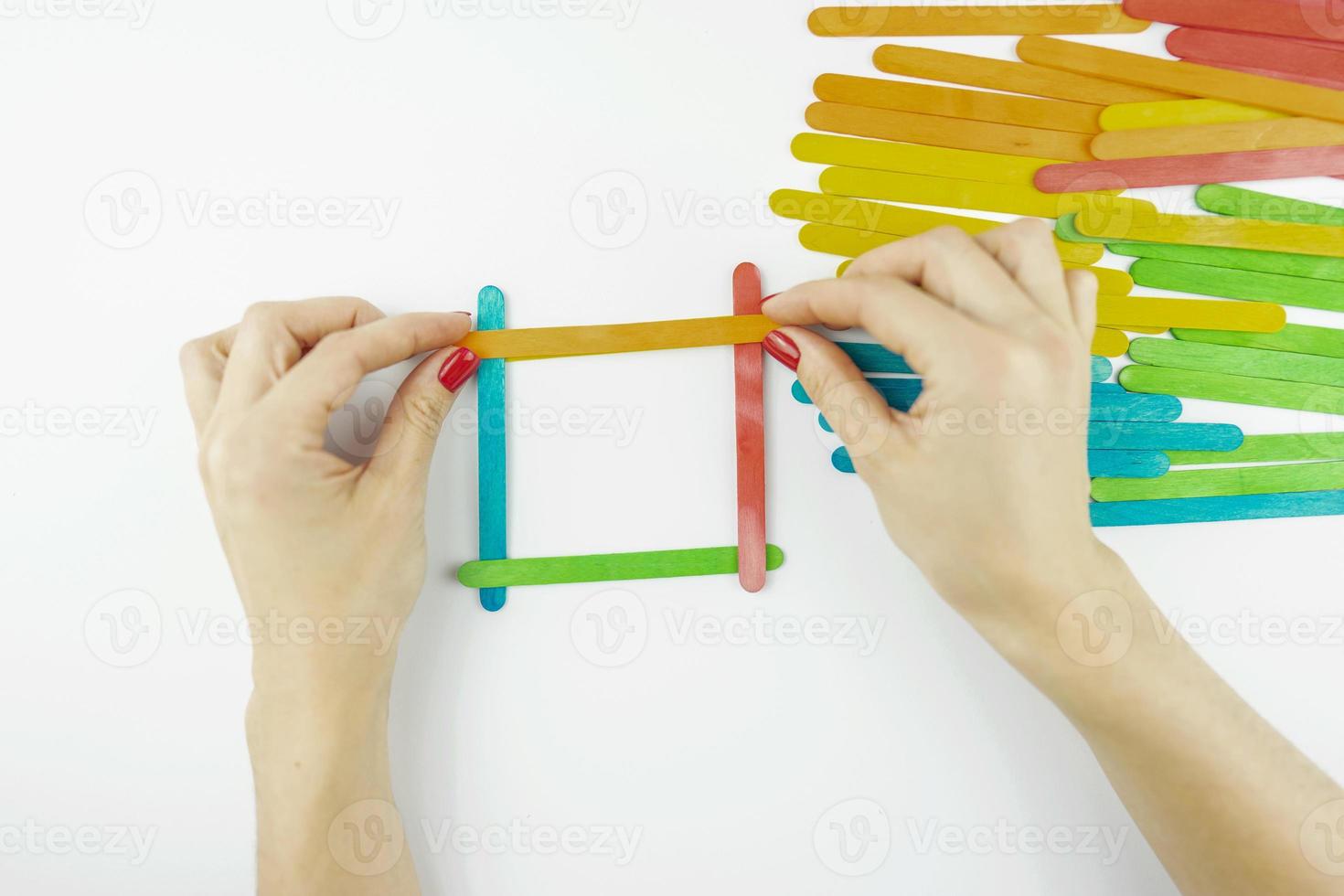 Women hands build a house of colorful sticks photo