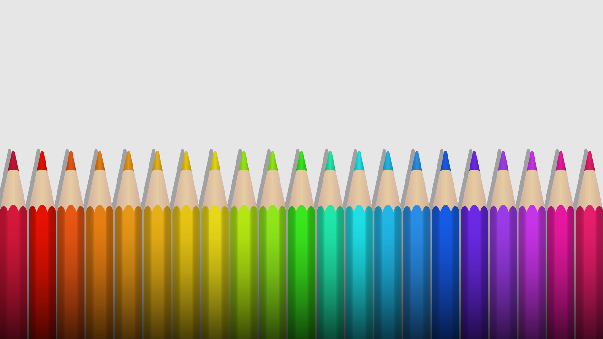 Rainbow colored pencils lie in a row on a white background