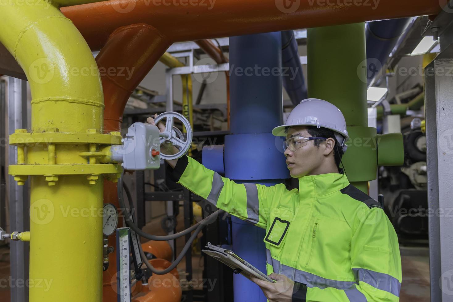 Asian engineer wearing glasses working in the boiler room,maintenance checking technical data of heating system equipment,Thailand people photo