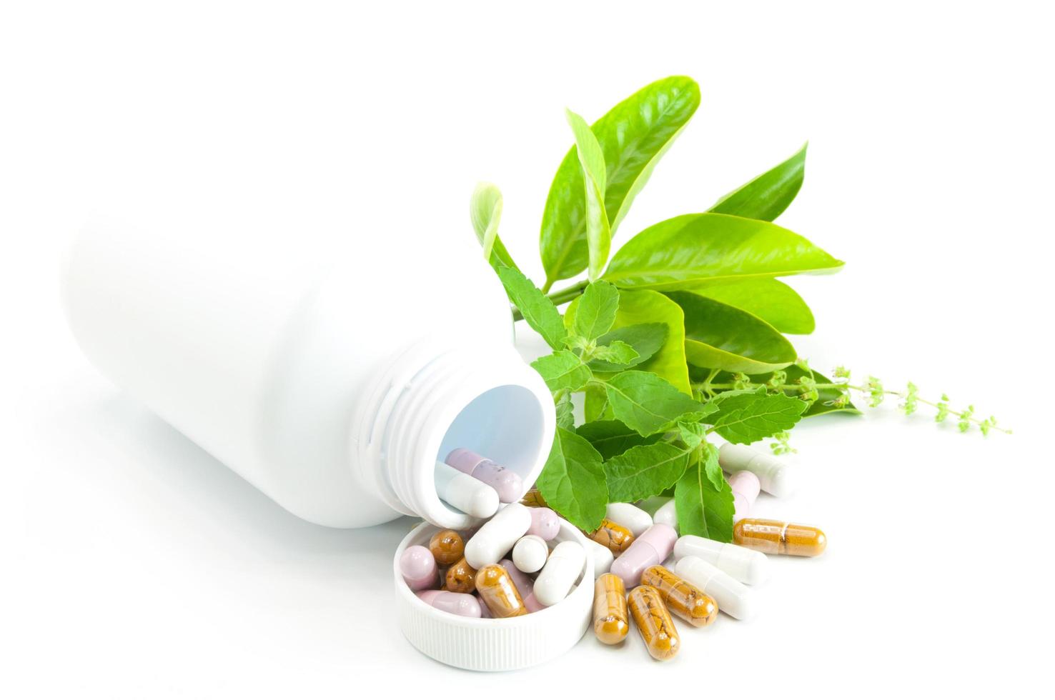 Herb capsule with green herbal leaf and bottle on white background. photo