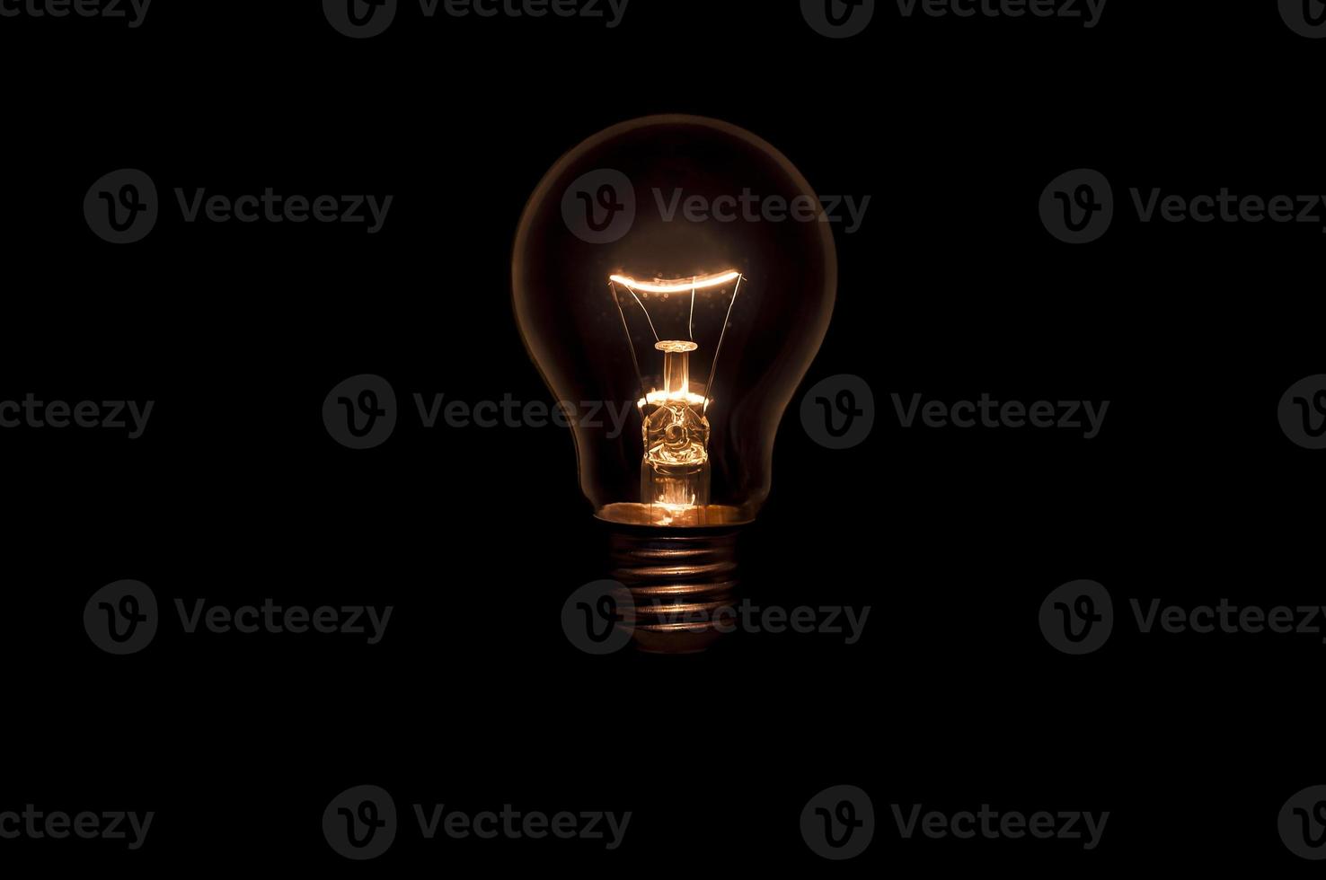 Tungsten light bulb without wiring and socket on black background. Concept for creative idea. photo