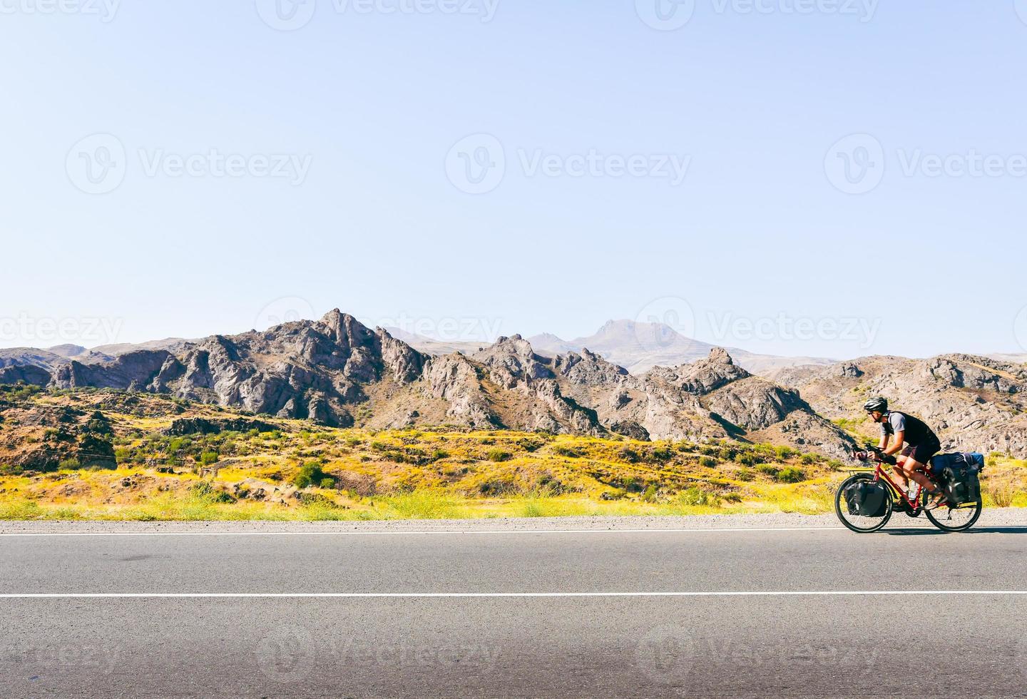 Aerial view caucasian male person solo cycle bicycle touring in countryside fully loaded with bags outdoors in summer heat. Creative ecological travel concept photo