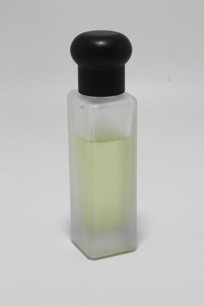 Frasco de perfume de vidrio de color claro y borroso aislado sobre fondo blanco foto