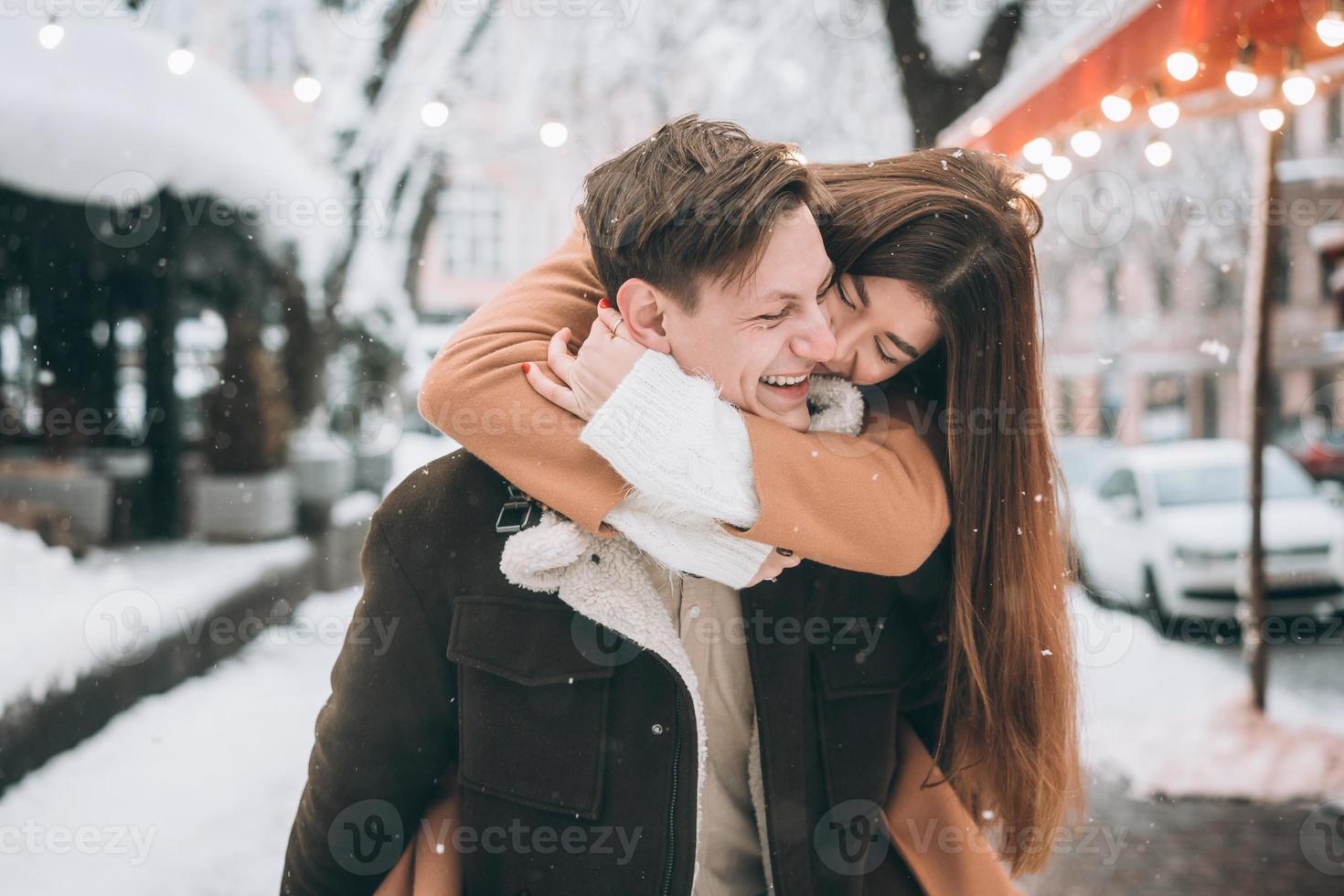 beautiful young couple having fun on a snowy street photo