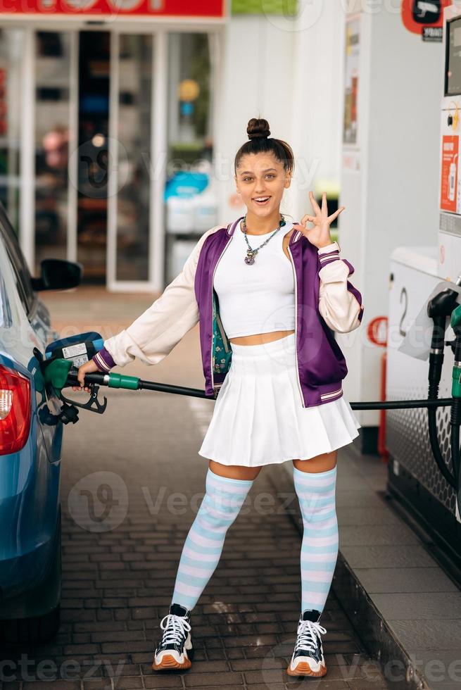 Woman filling her car with fuel at a gas station photo