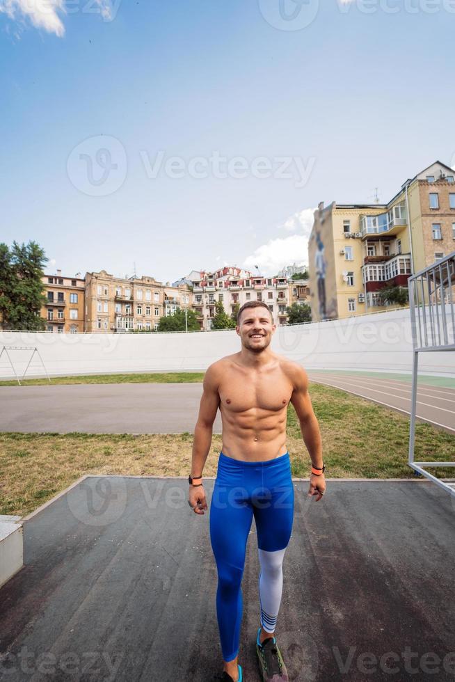Muscular guy with a naked torso in outdoor street gym. photo