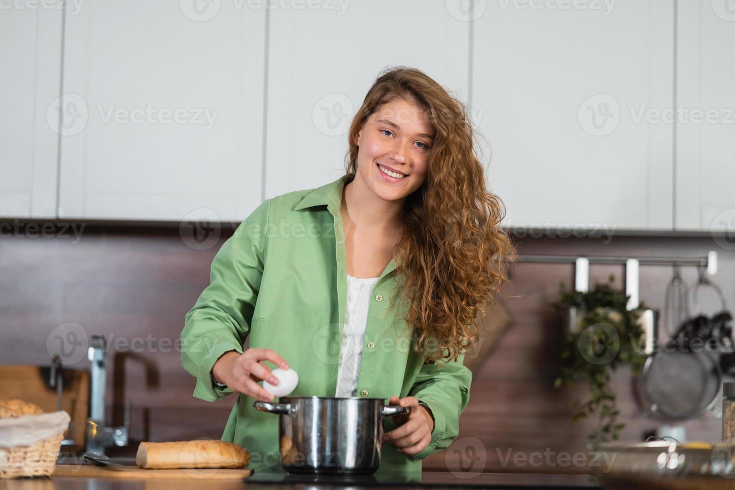 Young woman is preparing food in the kitchen. Beating eggs. photo