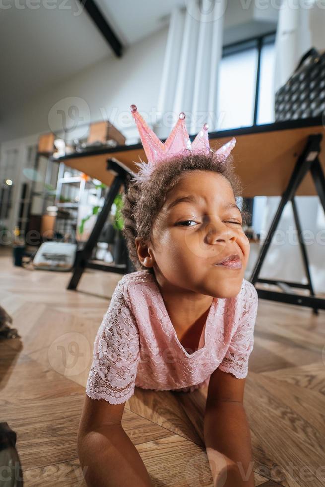 Little girl sitting on the floor grimacing at the camera photo