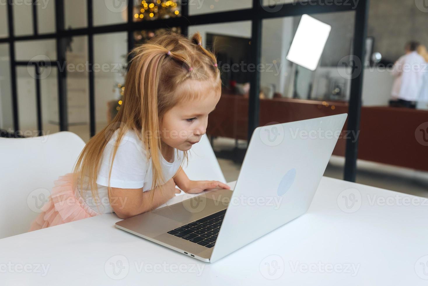Little girl using tablet computer sitting at table photo