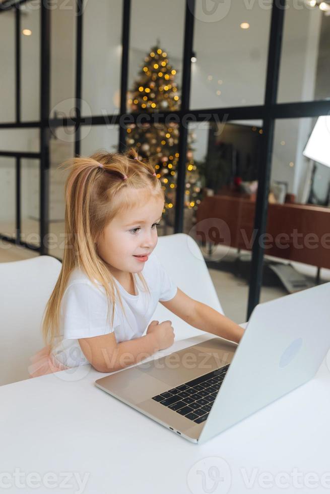 Little girl using tablet computer sitting at table photo