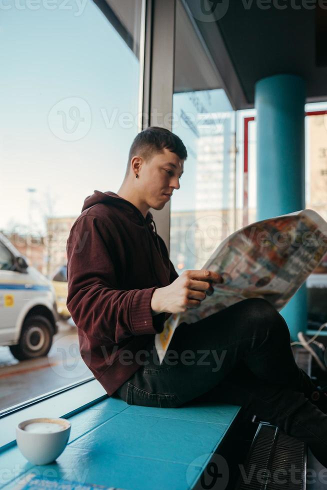Portrait of man sitting at a cafe, reading newspapers and drinking coffee photo