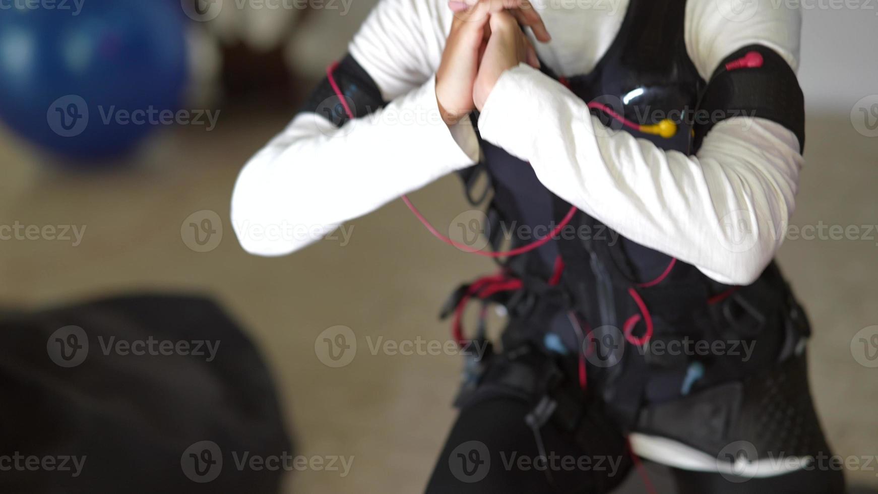 EMS training. Girl doing exercises in a suit with cables. photo