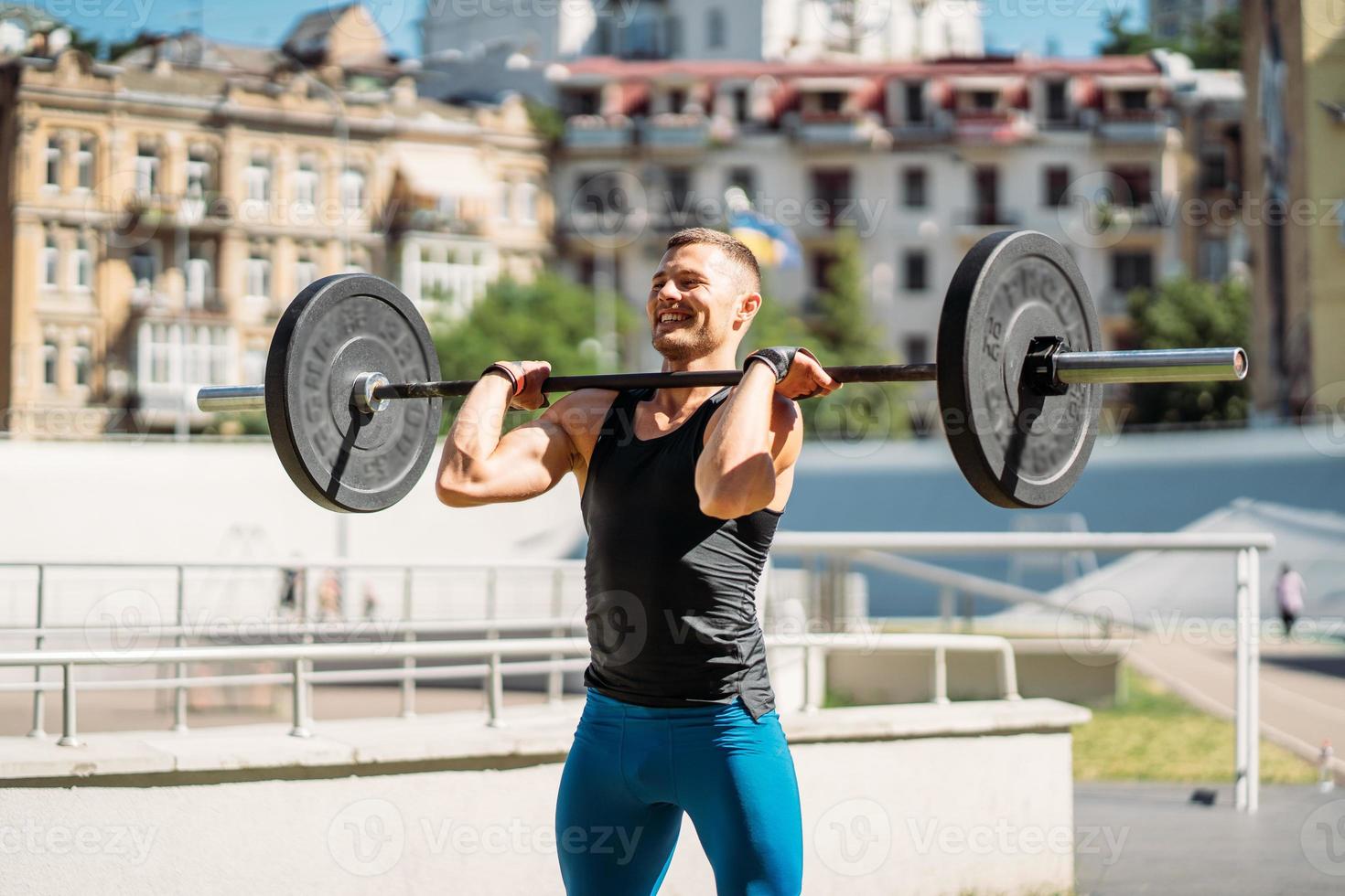 Young guy raises the bar in the stadium, outdoor workout photo