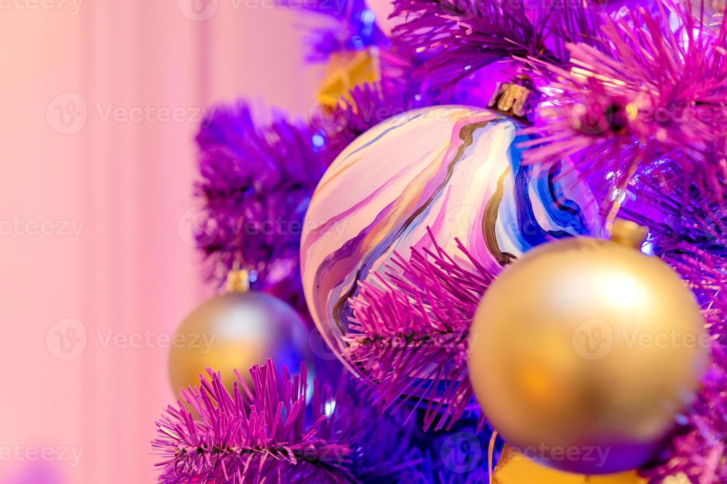 Violet neon christmas tree decorated wth gold baubles and garland. Festive greeting card for christmas and new year. photo