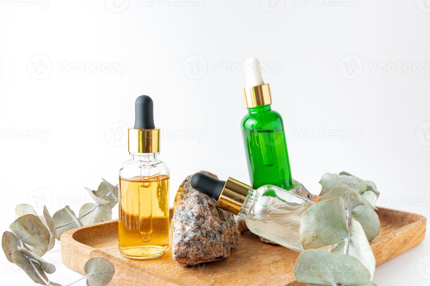 Dropper bottles with serum on wood tray. Natural facial essential oil or serum packaging without label. Beauty product branding mock-up. Cosmetic skincare concept. photo