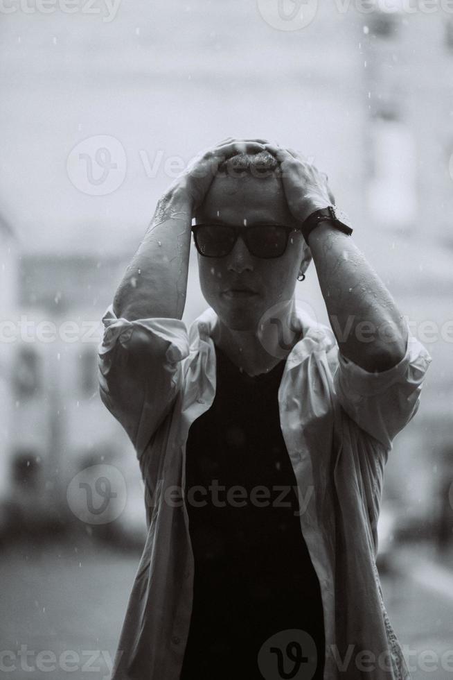 Portrait of carefree handsome young man is feeling free under the rain photo