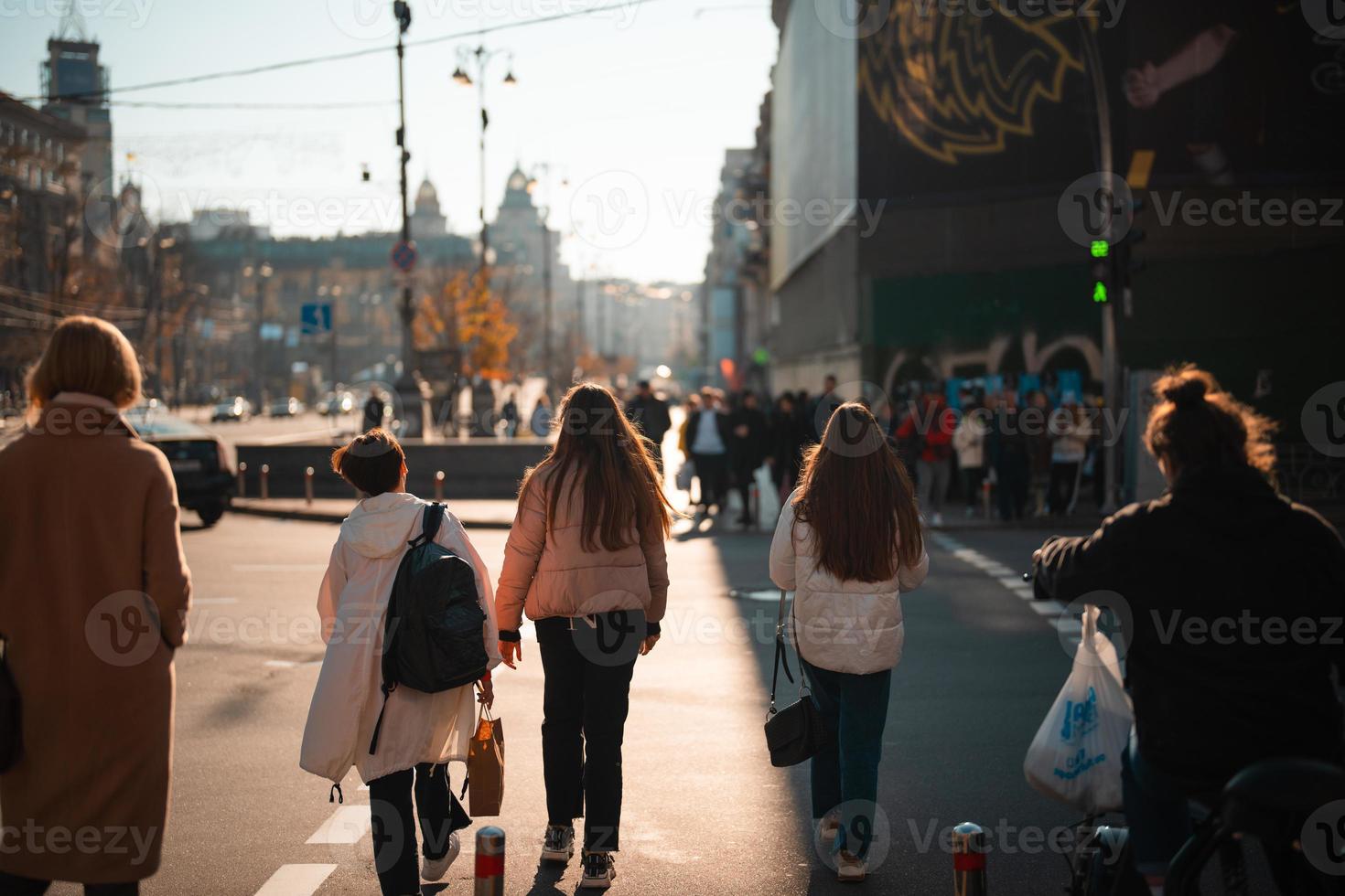 Lots of people crossing the street at the traffic lights. photo