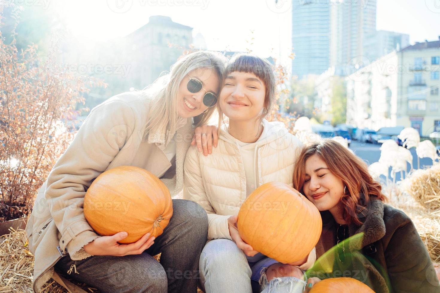 Girls holds pumpkins in hands on the background of the street. photo