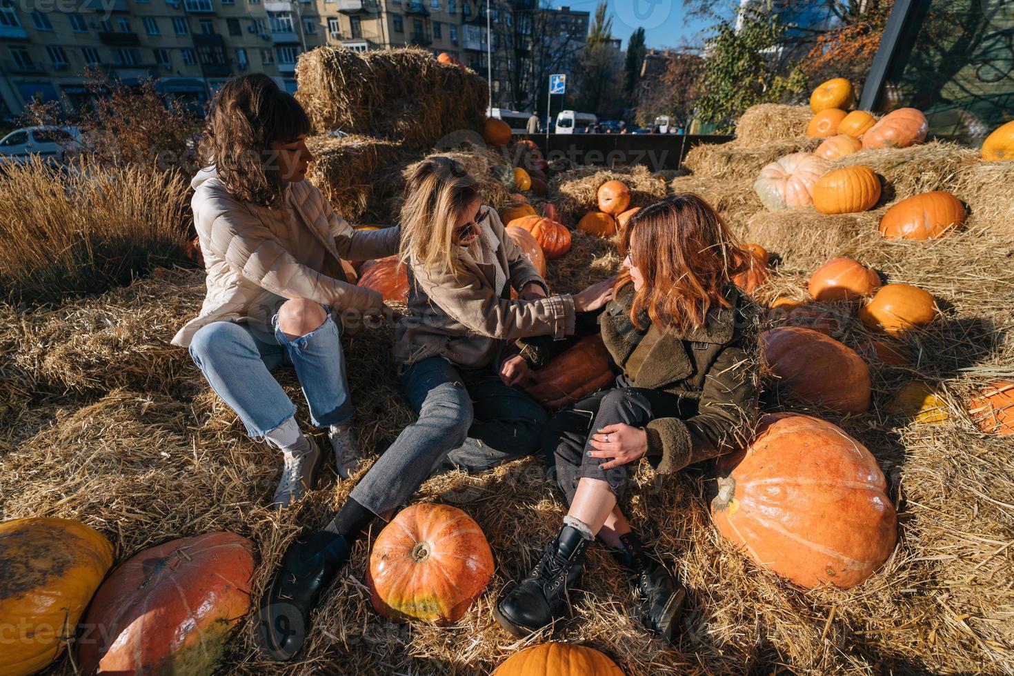 Young girls lie on haystacks among pumpkins. photo