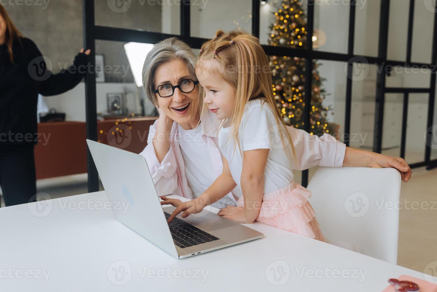 Child and granny looking at the camera with laptop photo