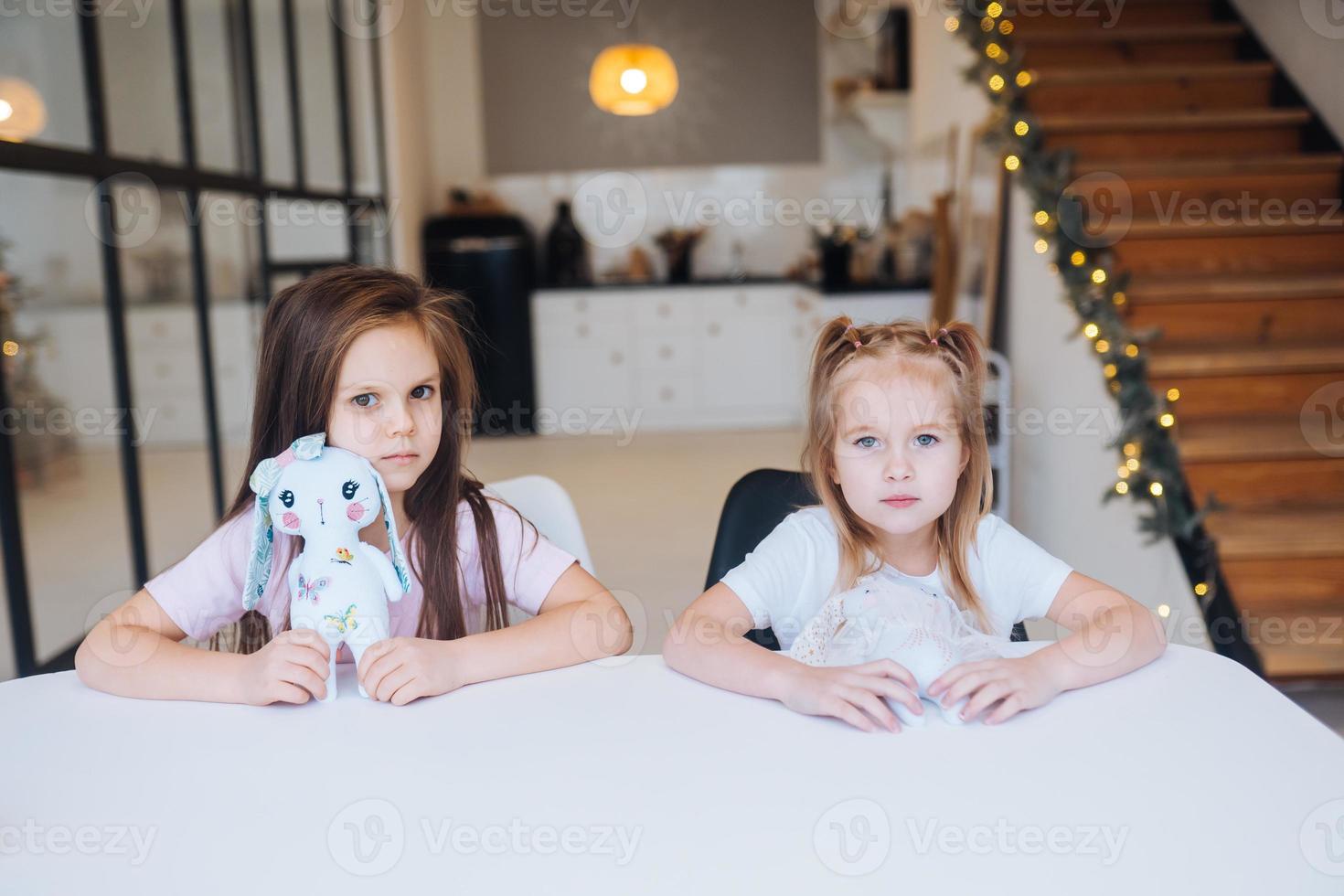 Two little sisters playing together at the table photo
