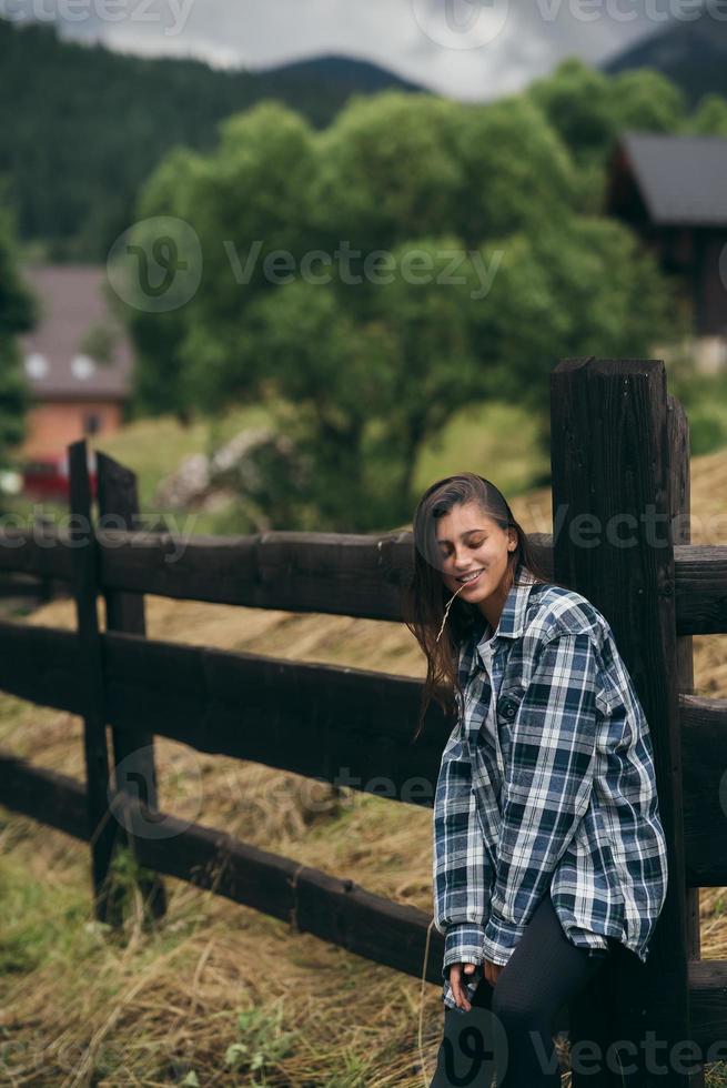 A young attractive Caucasian female stand by a fence photo