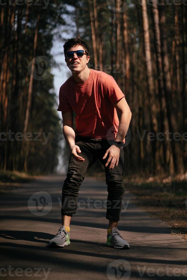 Handsome young man in white t-shirt and jeans outdoor in park, walking in the park photo