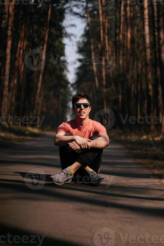 Handsome young man in white t-shirt and jeans outdoor in park, walking in the park photo