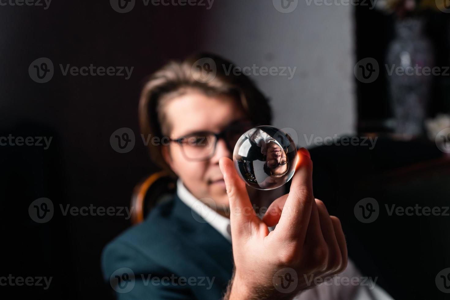Young man holding a clear transparent crystal glass ball in their hand photo