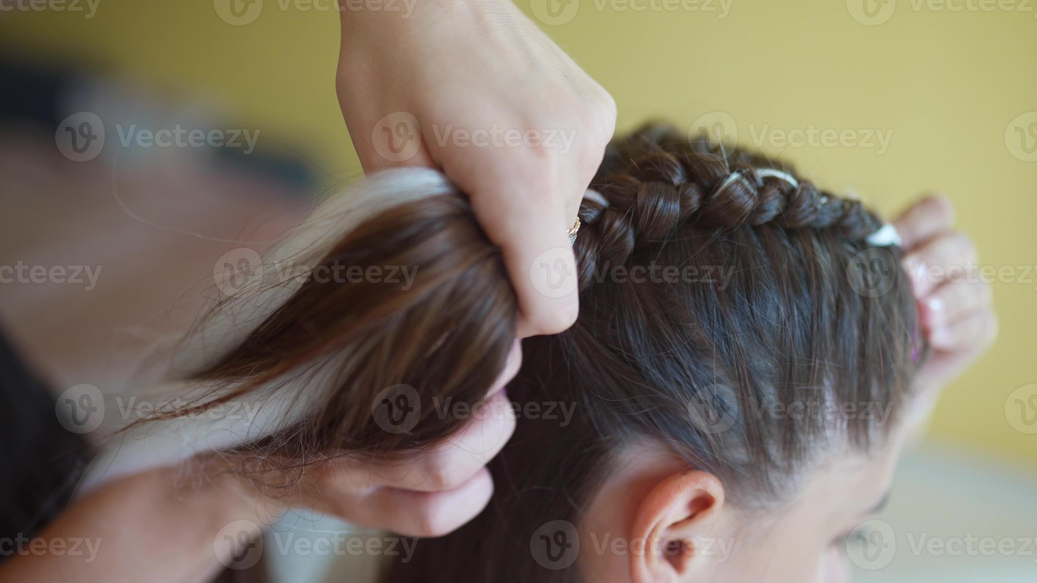 Process of braiding. Master weaves braids on head in a beauty