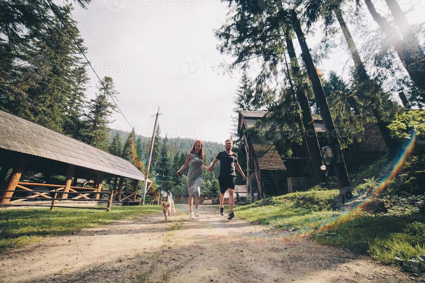 couple runs on road in the nature with dog photo