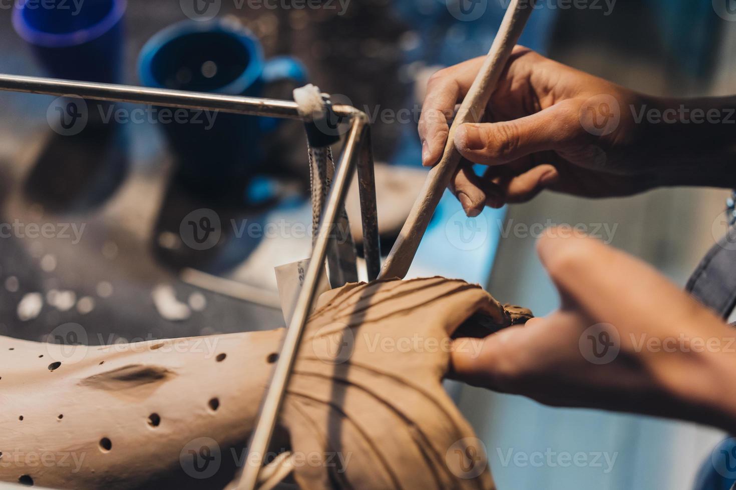 Close-up view of female hands gently handling a clay whale in workshop. photo