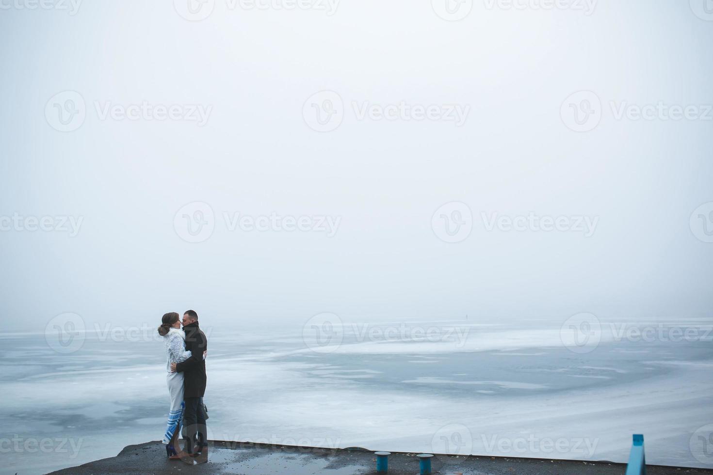 Beautiful couple on the dock in the winter fog. photo