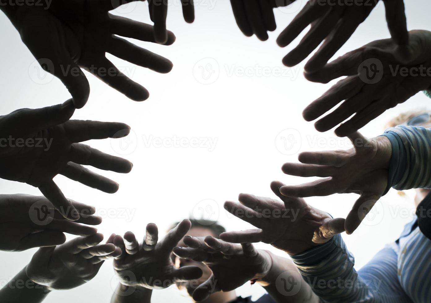 People's hands are folded in the sun and circle for team development and team building against the sky. The concept of unity, mutual support and mutual assistance. photo