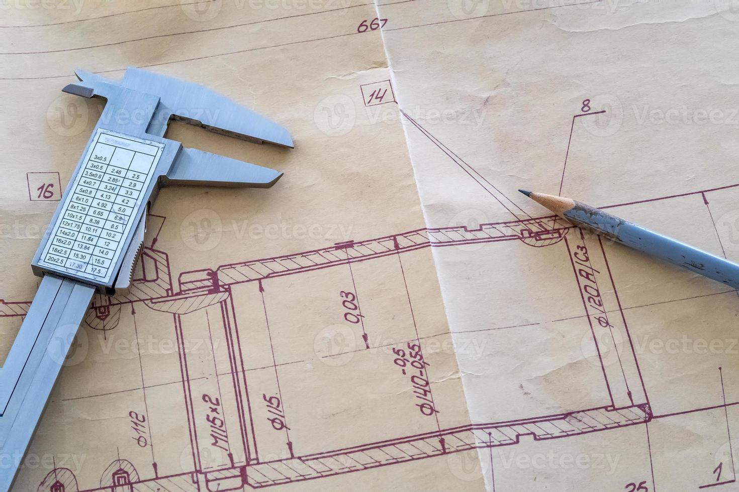 vista superior de una herramienta de medición de calibre y lápiz en un dibujo. dibujos de ingeniería, detalle de metal. foto