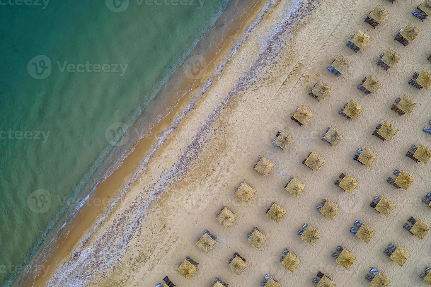vista aérea de una increíble playa con sombrillas de madera y mar en calma. foto