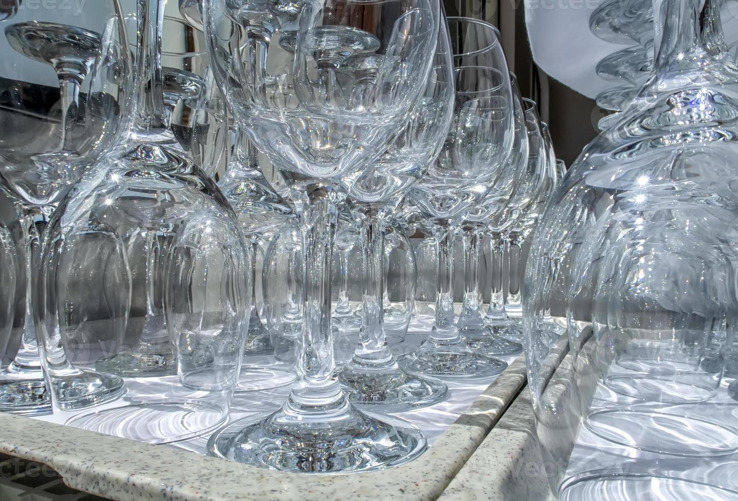 Rows of empty wine glasses close up. Glass goblets on the white table. Restaurant bar concept photo