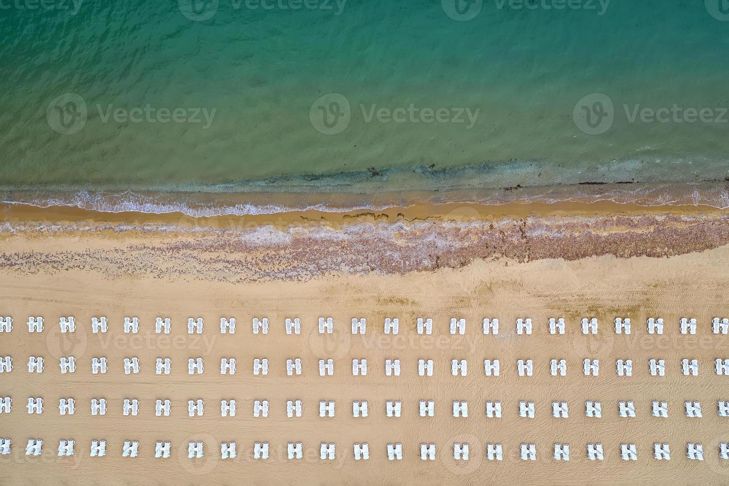 Aerial view of an amazing beach with white lounge chairs, and turquoise sea. photo
