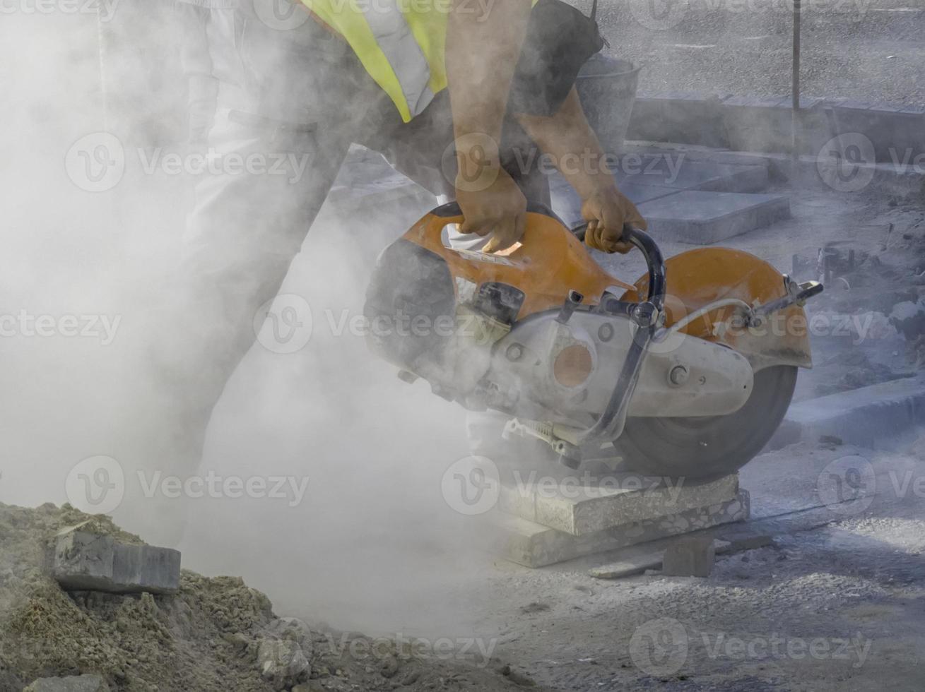 A worker cuts a tile to size with an electric grinder with many smoke. Pollution concept photo