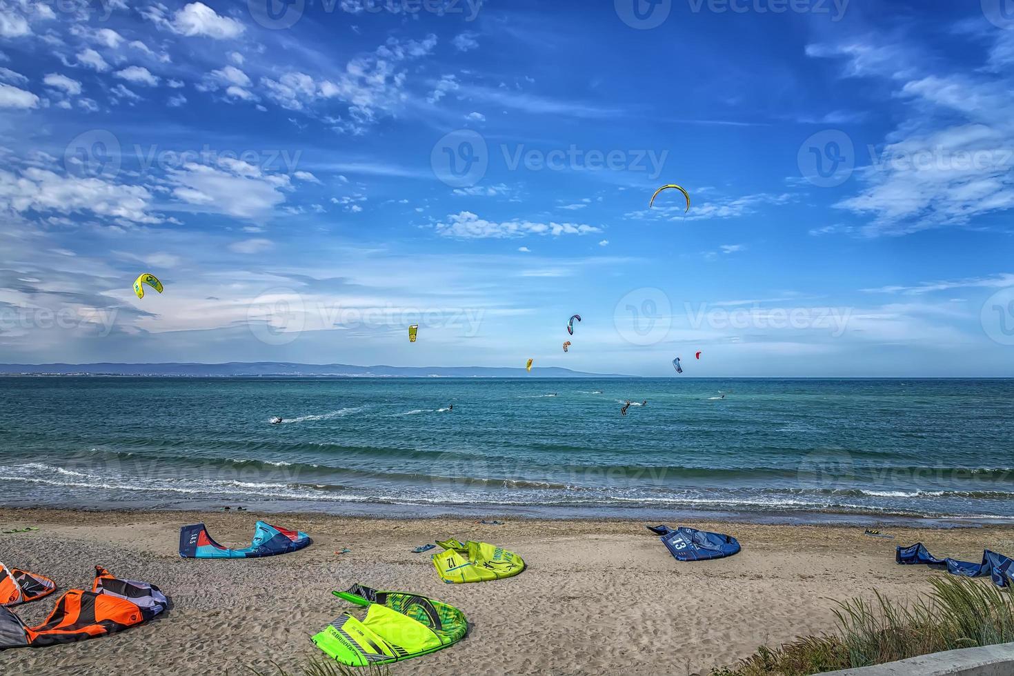 kitesurfistas surfeando el viento en las olas en un brillante día soleado de verano foto