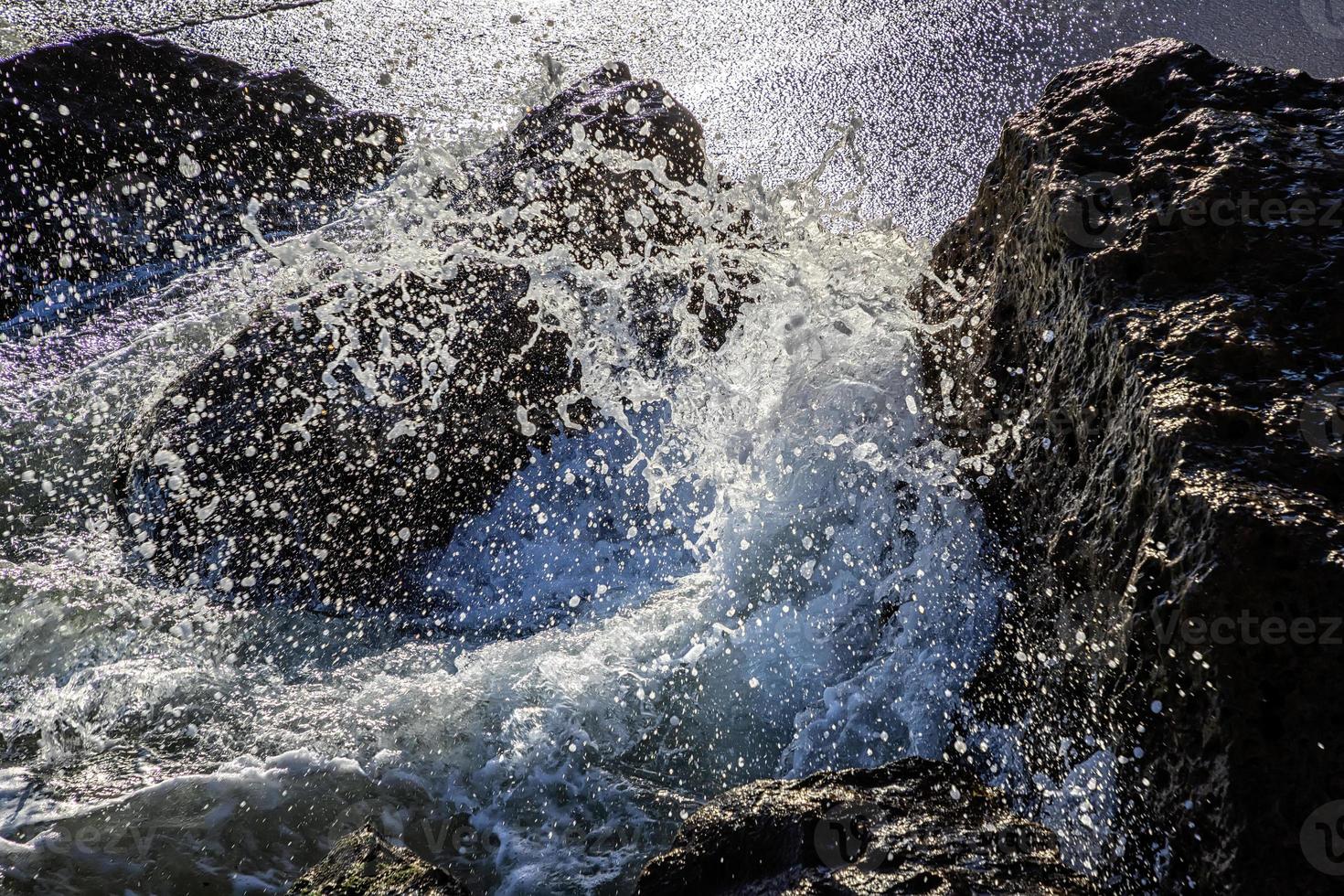 vista cercana de las olas del mar aplastadas contra las rocas. spray de agua de belleza foto