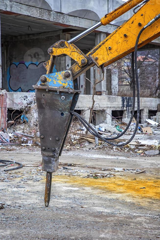 Arm of excavator with hydraulic breaker hammer for the destruction of concrete and hard rock at the construction site. Demolition equipment photo