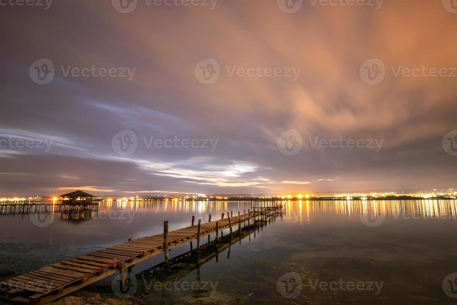 Beautiful night reflections in the sea from the port and moving clouds photo