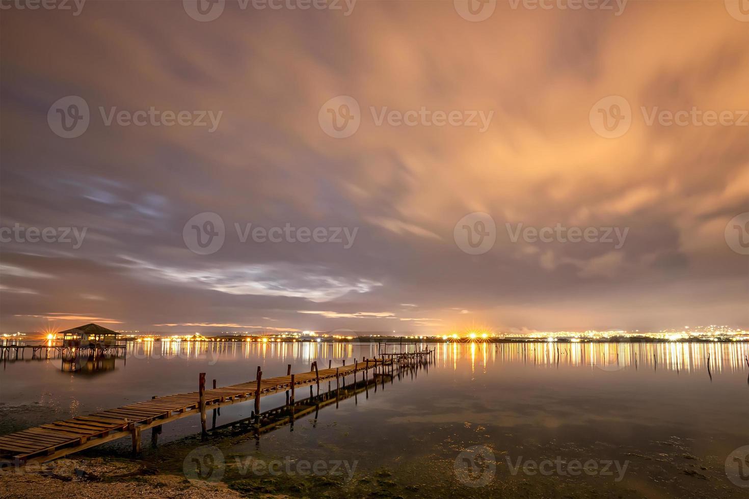 Beautiful night reflections in the sea from the port and moving clouds photo