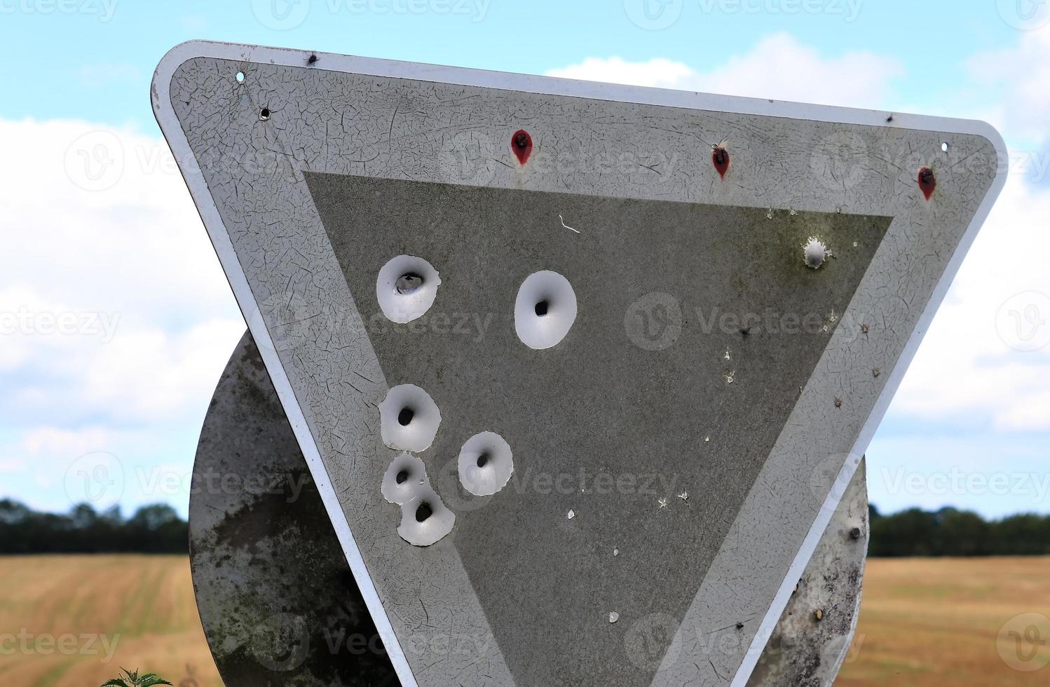 Detailed close up of bullet holes from gun shots in a traffic sign photo