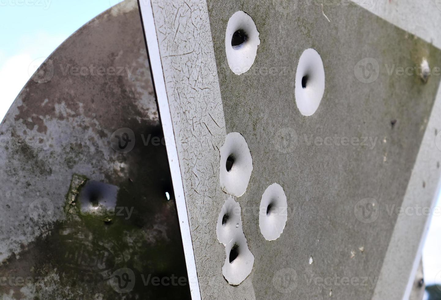 Detailed close up of bullet holes from gun shots in a traffic sign photo