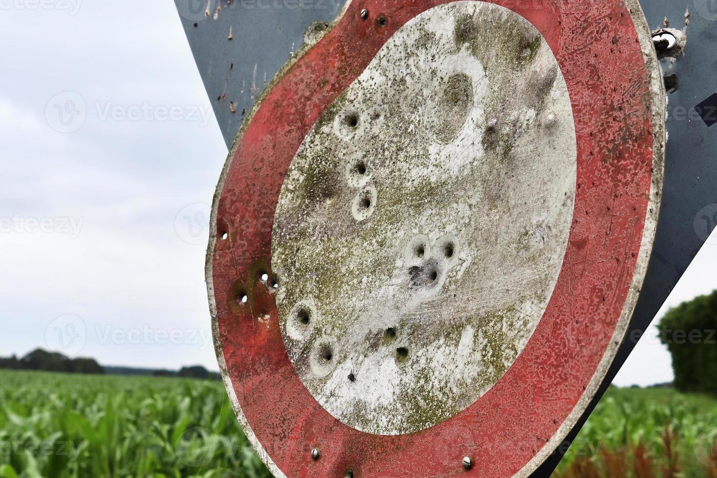 Detailed close up of bullet holes from gun shots in a traffic sign photo