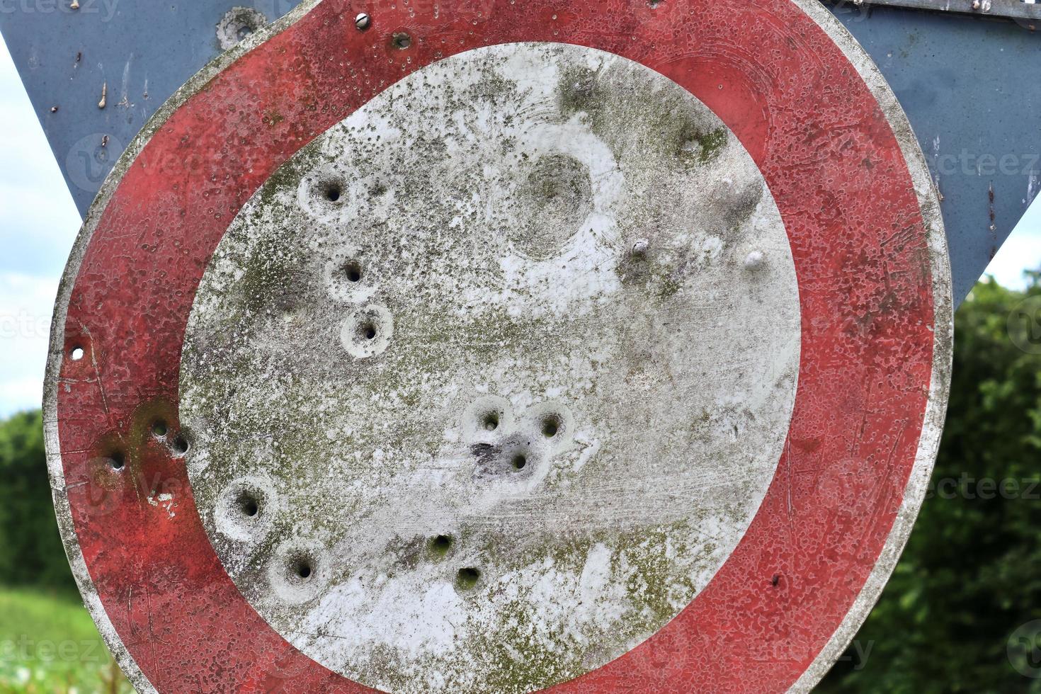 Detailed close up of bullet holes from gun shots in a traffic sign photo