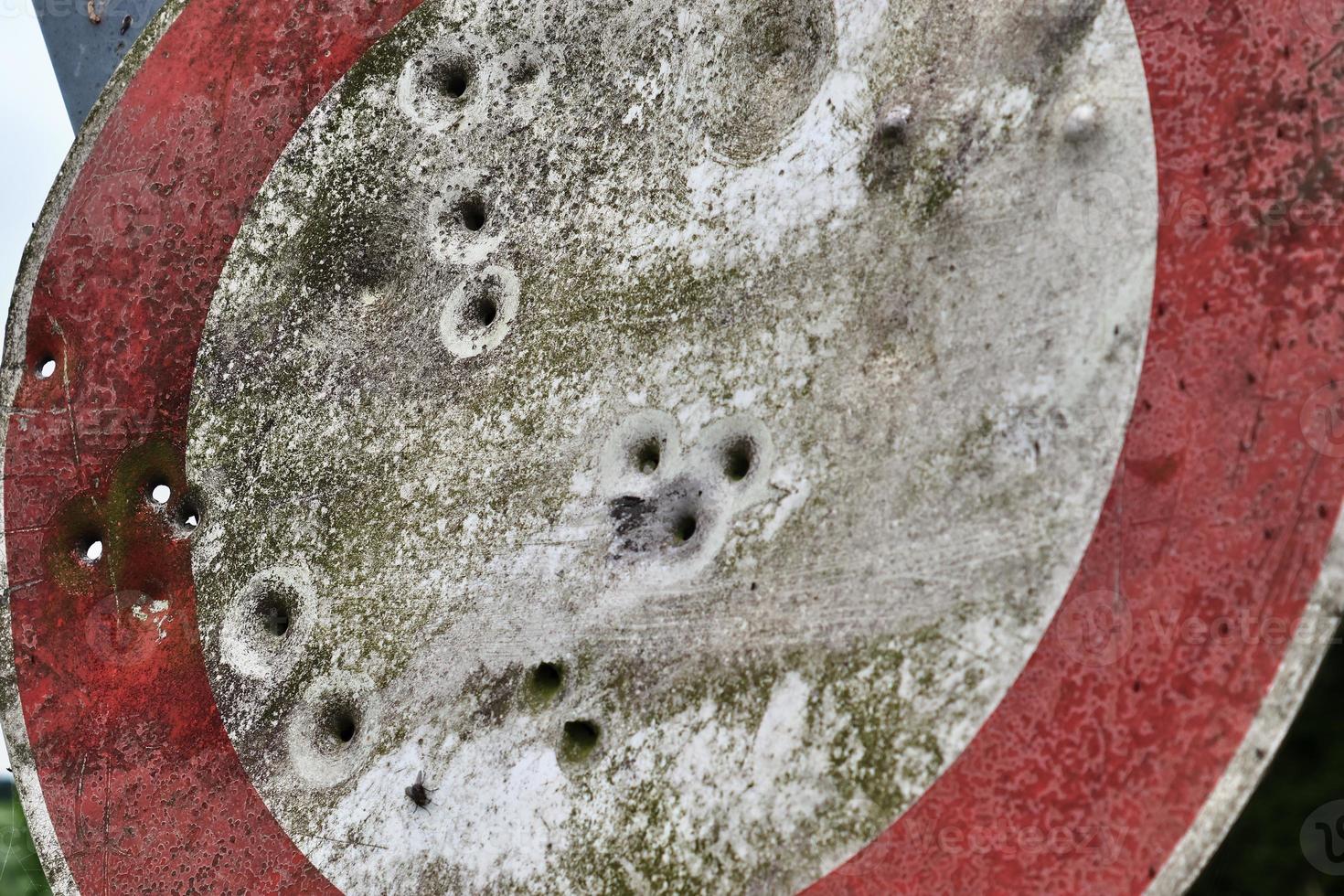 Detailed close up of bullet holes from gun shots in a traffic sign photo